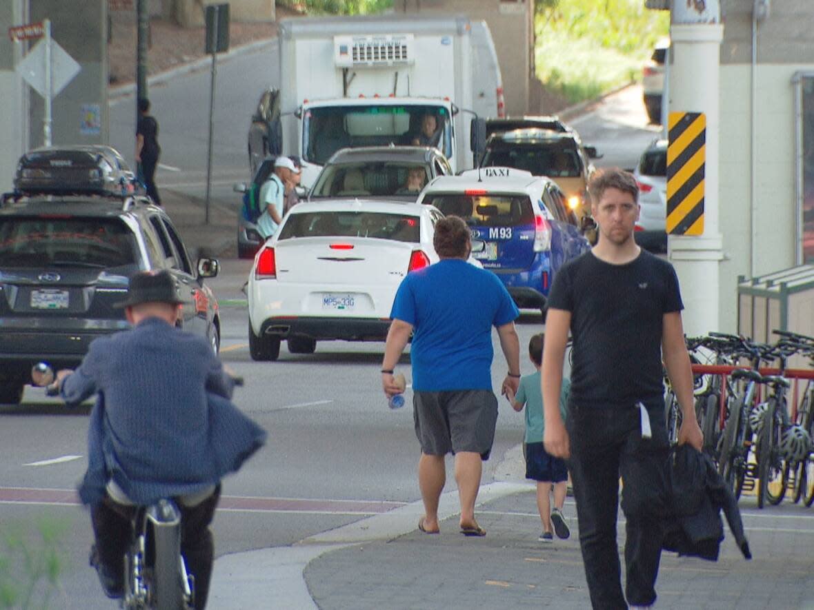 People walk on Granville Island with cars passing by. Last week, a concerned citizen in Vancouver wrote a Reddit post suggesting the popular tourist destination should go car-free on weekends, and it has earned nearly 2,000 upvotes. (Radio-Canada - image credit)