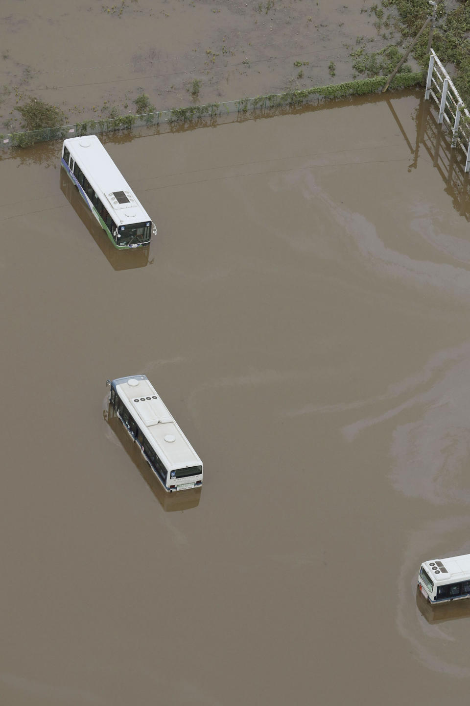 Busses are submerged in floodwaters after torrential rain in Sakura city, Chiba prefecture, east of Tokyo, Saturday, Oct. 26, 2019. Torrential rain that caused flooding and mudslides in towns east of Tokyo added damage in areas still recovering from recent typhoons. (Kyodo News via AP)
