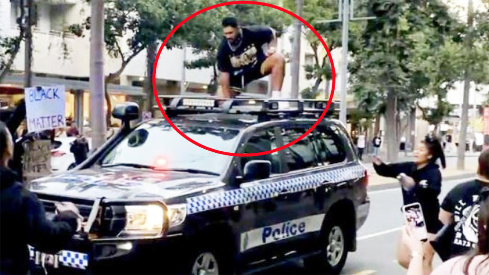 Cruz Topai-Aveai, pictured here on top of a police car at a protest in Brisbane.