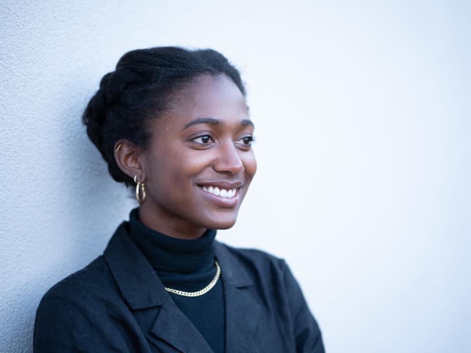 A woman wearing all black smiles beyond the camera