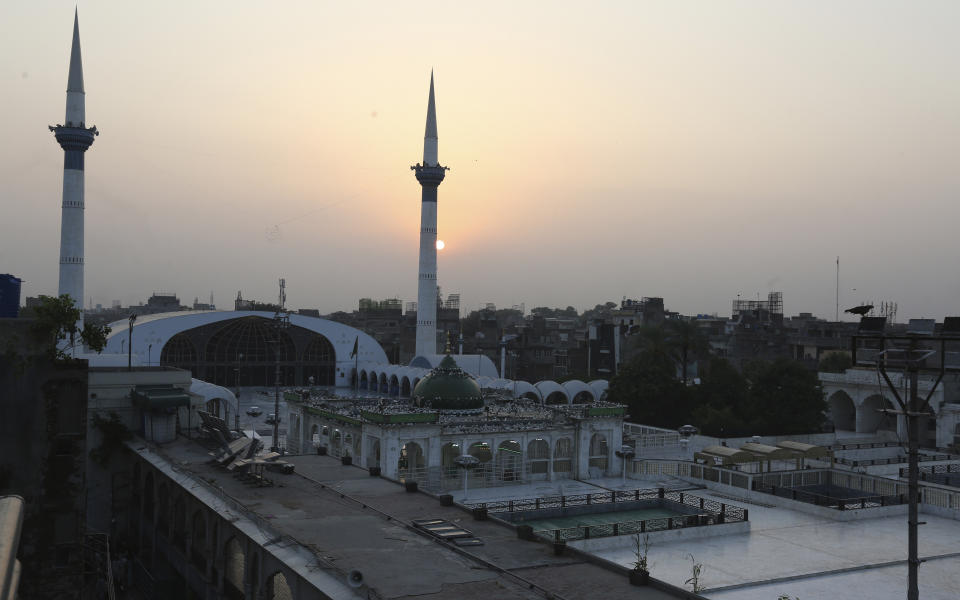 The sun sets through the shrine of a famous saint Ali Al-Hajweri known as Data Darbar, which is closed due to new restrictions announced by government to help control the spread of the coronavirus, in Lahore, Pakistan, Friday, Aug. 6, 2021. (AP Photo/K.M. Chaudhry)