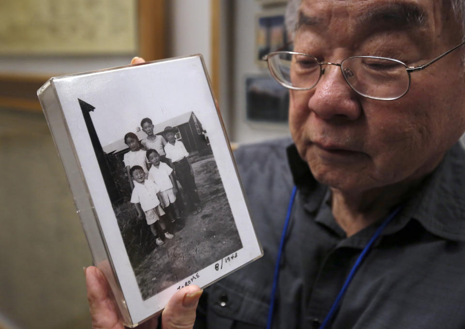 In this photo taken Tuesday, Feb. 11, 2020, Les Ouchida holds a 1943 photo of himself, front row, center, and his siblings taken at the internment camp his family was moved to, as he poses at the permanent exhibit titled "UpRooted Japanese Americans in World War II" at the California Museum in Sacramento, Calif. Ochida, who is a docent for the exhibit, and his family were forced to move in 1942 from their home near Sacramento to a camp in Jerome, Arkansas. Assemblyman Al Muratsuchi, D-Torrence has introduced a resolution to apologize for the state's role in carrying out the federal government's internment of Japanese-Americans. A similar resolution will be brought up before the state Senate by Sen. Richard Pan, D-Sacramento.(AP Photo/Rich Pedroncelli)