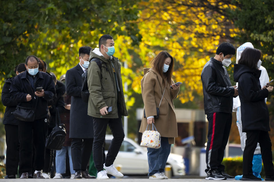 People wearing face masks stand in line for COVID-19 tests at a coronavirus testing site in Beijing, Wednesday, Nov. 16, 2022. Chinese authorities locked down a major university in Beijing on Wednesday after finding one COVID-19 case as they stick to a "zero-COVID" approach despite growing public discontent. (AP Photo/Mark Schiefelbein)