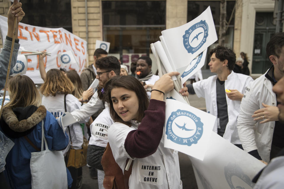 In this photo taken on Dec.17, 2019, Smranda Deaconu passes out flags at a hospital workers march in Marseille, southern France. In a hospital in Marseille, student doctors are holding an exceptional, open-ended strike to demand a better future. France’s vaunted public hospital system is increasingly stretched to its limits after years of cost cuts, and the interns at La Timone - one of the country’s biggest hospitals - say their internships are failing to prepare them as medical professionals. Instead, the doctors-in-training are being used to fill the gaps. (AP Photo/Daniel Cole)