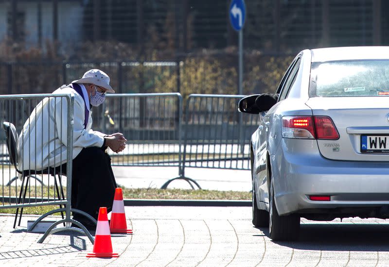 FILE PHOTO: A priest wearing a protective mask gives a "drive-in confession" in front of a church following the coronavirus disease (COVID-19) outbreak in Warsaw