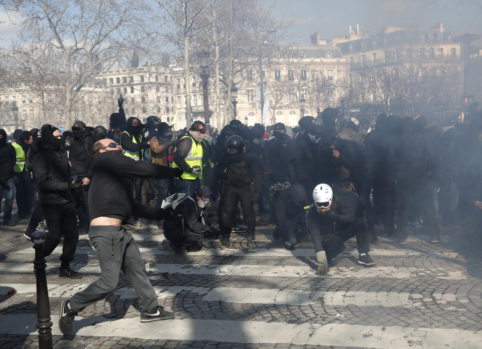 Youth clash with police forces during a yellow vests demonstration Saturday, March 16, 2019 in Paris. French yellow vest protesters clashed Saturday with riot police near the Arc de Triomphe as they kicked off their 18th straight weekend of demonstrations against President Emmanuel Macron. (AP Photo/Christophe Ena)