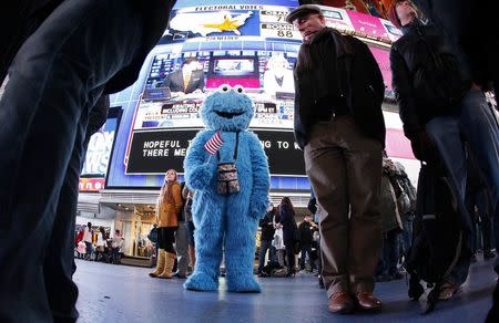 A man dressed as the character Cookie Monster watches TV screens in Times Square giving U.S presidential election results in New York in a November 6, 2012 file photo. REUTERS/Carlo Allegri/Files