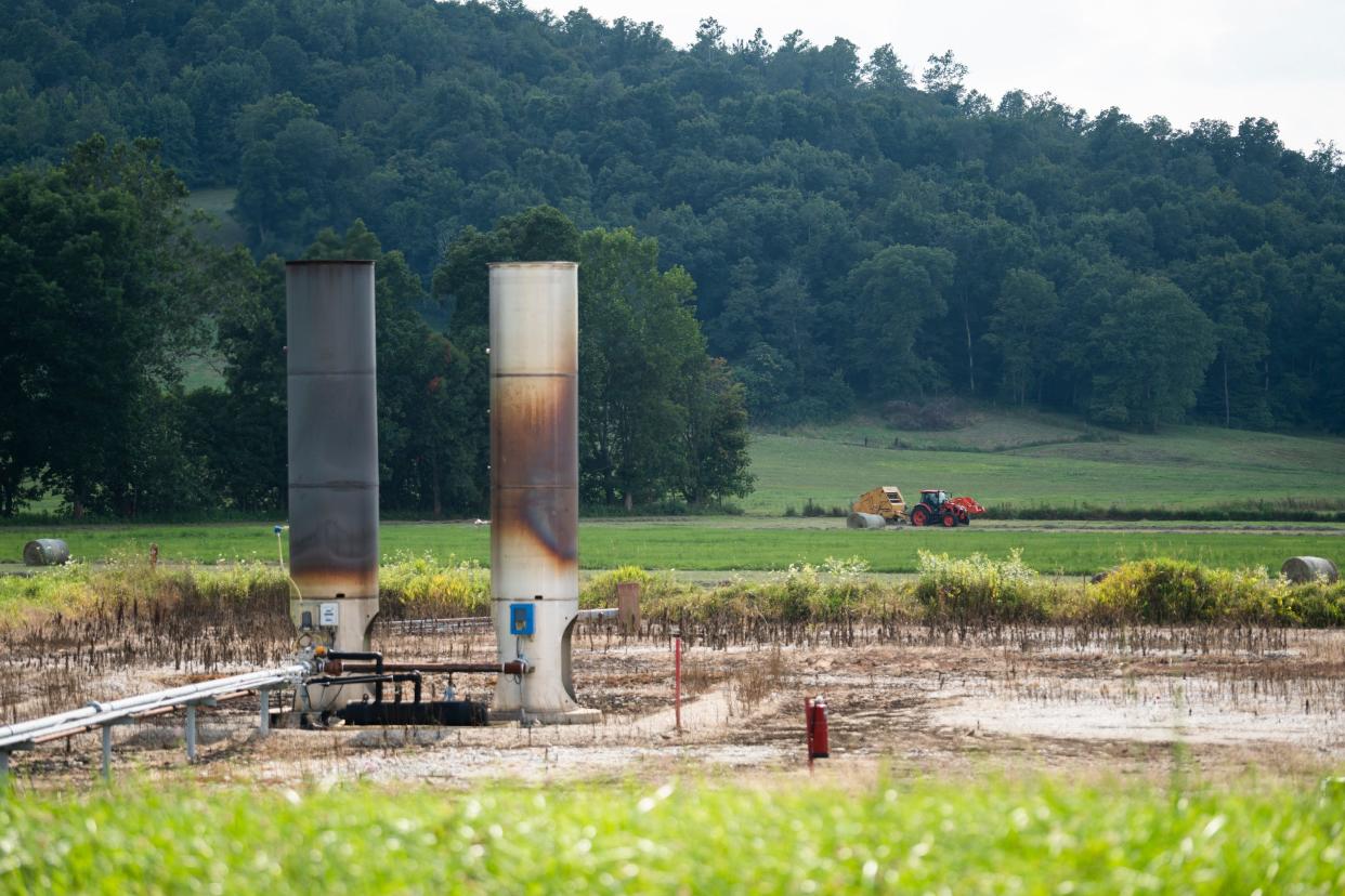 Aug 4, 2023; Cambridge, Ohio, USA; A farmer bails hay right next to a well pad in Guernsey County. Applications have come in to frack beneath Salt Fork State Park in Guernsey County and Wolf Run State Park in Noble County