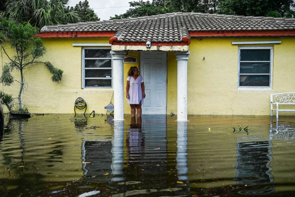 PHOTO: FILE - A woman looks on as she stands outside of his flooded home after heavy rain in Fort Lauderdale, Fla., April 13, 2023. (Chandan Khanna/AFP via Getty Images, FILE)