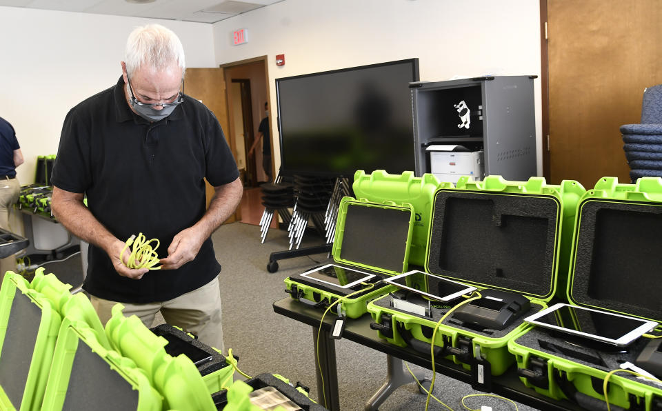 FILE - Mark Splonskowski assembles electronic poll book kits that voters will use to sign in at polling locations at the Albany County Board of Elections building, Oct. 14, 2020, in Albany, N.Y. An effort to create a national testing program for technology central to U.S elections will get underway later this year. The aim is to strengthen the security of equipment that's been targeted by foreign governments and that's provided fertile ground for conspiracy theories. (AP Photo/Hans Pennink, File)
