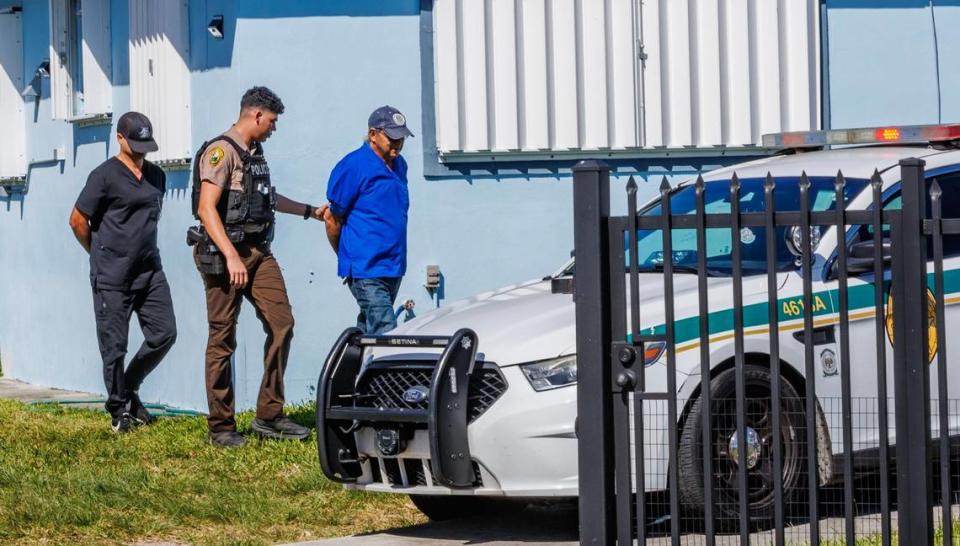 An police officer takes two handcuffed men out of a house, located at 11901 SW 185 Terrace in southwest Miami-Dade County, where Miami-Dade detectives served a warrant Saturday, Jan. 27, 2024, following an anonymous tip that an illegal veterinarian clinic was operating at the property.