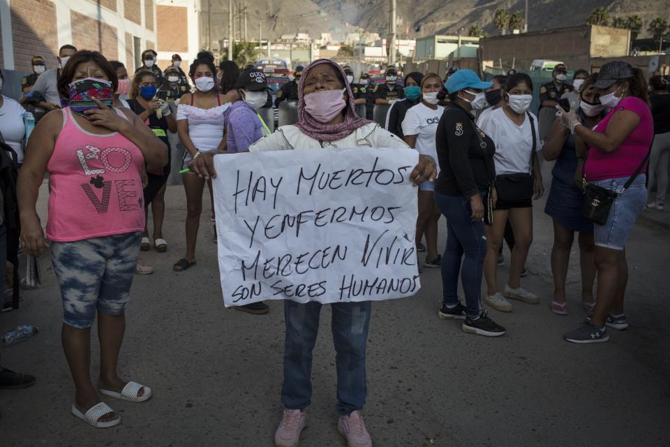 A woman holds a sign that reads in Spanish "There are dead and sick. They deserve to live. They are human beings," as relatives of the inmates gather outside Castro Castro prison in Lima, Peru, Monday, April 27, 2020. Peru's prison agency reported that three prisoners died from causes still under investigation after a riot at the Miguel Castro Castro prison in Lima. Inmates complain authorities are not doing enough to prevent the spread of coronavirus inside the prison. (AP Photo/Rodrigo Abd)