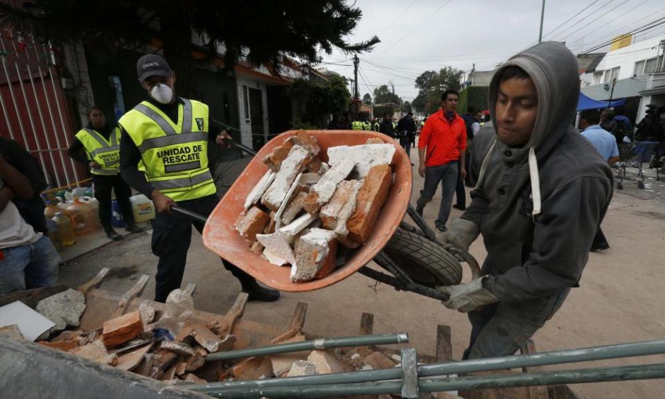 A man moves rubble taken from the Enrique Rebsamen school that collapsed after an earthquake in Mexico City.