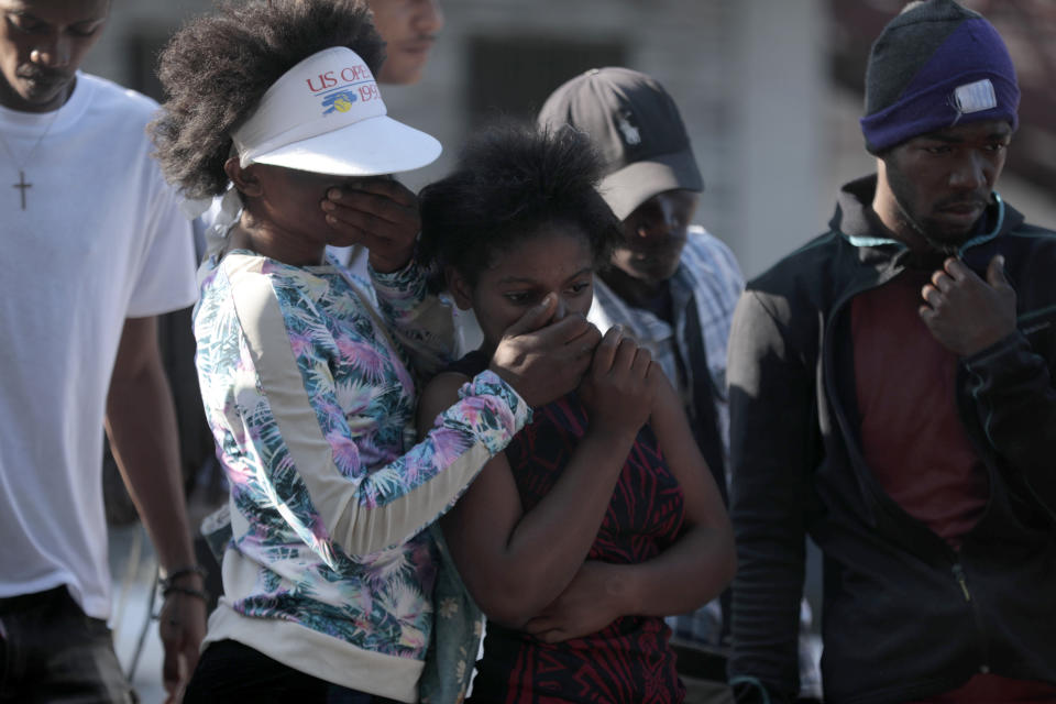 Bystanders look at the bodies of alleged gang members that were set on fire by a mob after they were stopped by police while traveling in a vehicle in the Canape Vert area of Port-au-Prince, Haiti, Monday, April 24, 2023. (AP Photo/Odelyn Joseph)