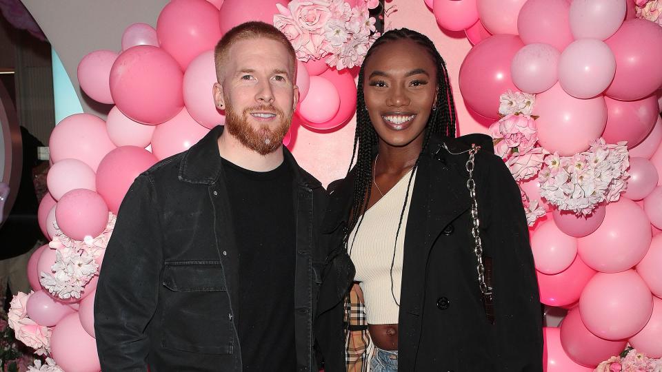 Chyna Mills and Neil Jones smiling together in front of a balloon wall