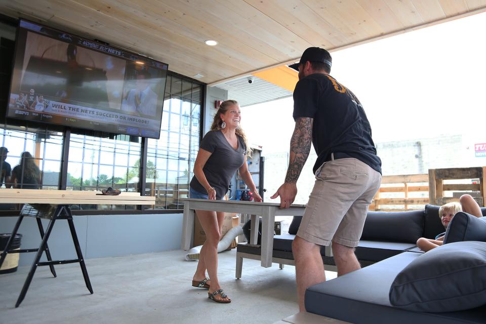 From left, co-owner Cambrea Fisher and general manager John Crittenden assemble the furniture at the outdoor seating area of Wing-Itz in Hampton on Wednesday, August 24, 2022.