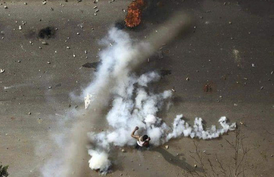 FILE - In this Dec. 21, 2018 file handout photo provided a Sudanese activist, a protester stands in tear gas during clashes with security forces in Khartoum, Sudan. The anti-government protests rocking Sudan for the past month are reminiscent of the Arab Spring uprisings of nearly a decade ago. Demonstrators, many in their 20s and 30s, are trying to remove President Omar al-Bashir, an authoritarian leader, and win freedoms and human rights. (Sudanese Activist via AP, File)