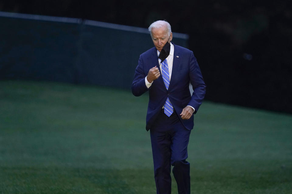 President Joe Biden takes off his mask as he walks off of Marine One on the South Lawn of the White House in Washington, Tuesday, Oct. 5, 2021, after returning from a trip to Michigan to promote his infrastructure plan. (AP Photo/Susan Walsh)
