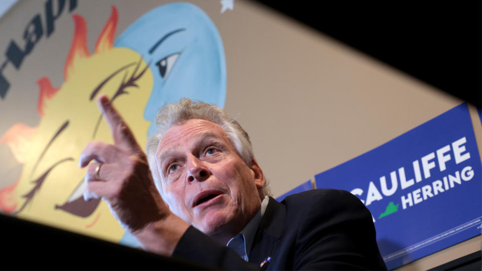 Former Virginia Gov. Terry McAuliffe stands at a podium in front of a campaign sign.