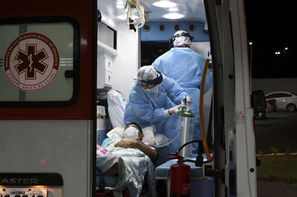 In this April 14, 2020 photo, health workers help a patient suffering COVID-19 disease, as they arrived to the field municipal Hospital Gilberto Novaes, in Manaus, Brazil. In cities like Manaus that have a dearth of equipment and ICU beds, lack of compliance with measures for social distancing is pushing the health care system to its breaking point. (AP Photo/Edmar Barros)