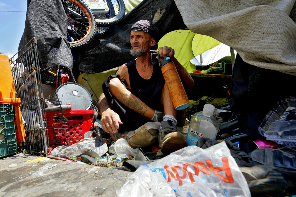Charles Sanders, 59, sits in his tent inside a homeless encampment called "The Zone," Friday, July 14, 2023, in downtown Phoenix. Sanders, from Denver, has been spending the days at the Justa Center, a day center for homeless people 55 years and older in the downtown area. (AP Photo/Matt York)