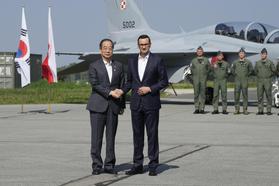 South Korean Prime Minister Han Duck-Soo, left, and his Polish host, Prime Minister Mateusz Morawiecki, right, shake hands following talks on regional security and the examination of the FA-50 fighter jets that Poland recently bought from South Korea, along with other military equipment, at an air base in Minsk Mazowiecki, eastern Poland, Wednesday, Sept. 13, 2023. Han was in Poland for talks on regional security amid war in neighboring Ukraine, and also to discuss military and nuclear energy cooperation. (AP Photo/Czarek Sokolowski)