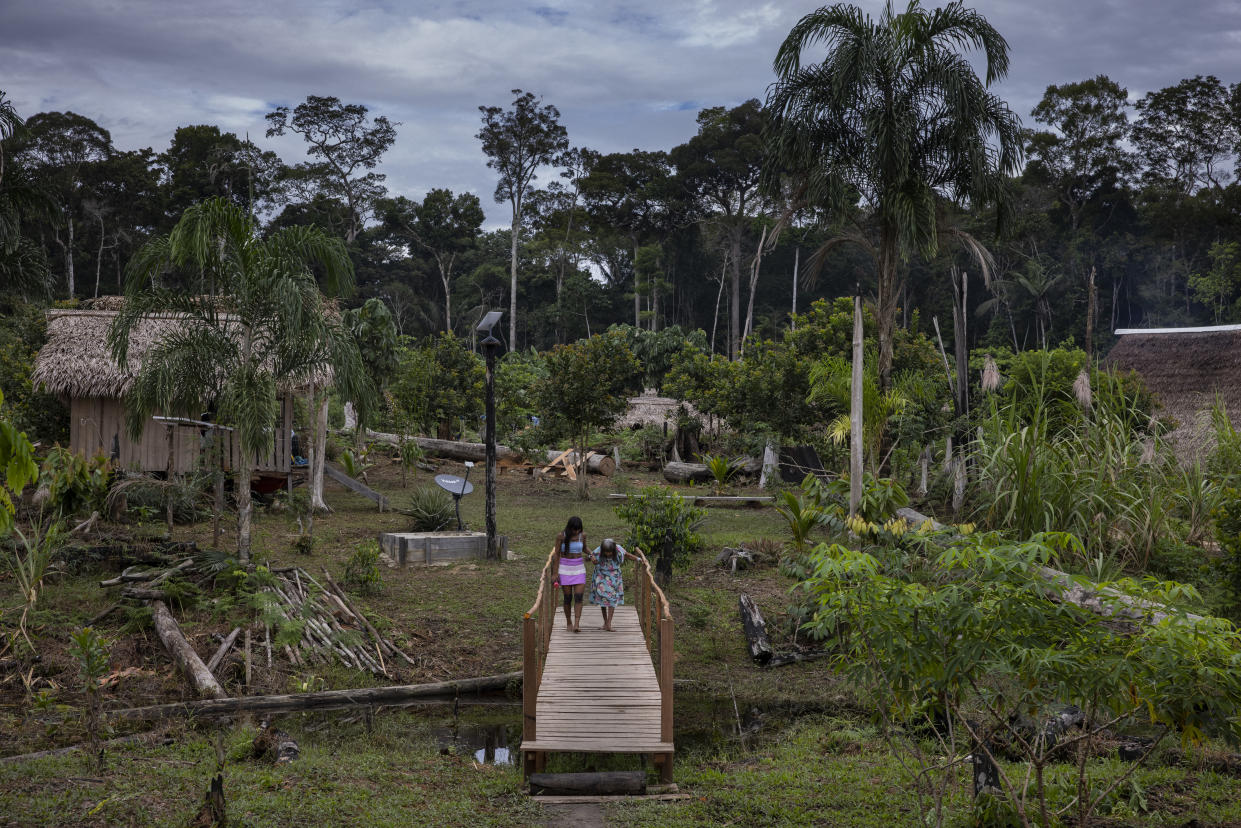 Varî Vãti Marubo, quien quizá sea una de las personas más ancianas que todavía viven en las profundidades del bosque tropical de la Amazonía, recibe ayuda para cruzar un puente en la Tierra Indígena Marubo, en el estado Acre de Brasil, el 7 de abril de 2024. (Victor Moriyama/The New York Times)