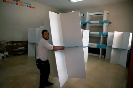 A staff member of Guatemala's Supreme Electoral Tribunal (TSE) carries a screen as he sets up voting equipment ahead of the second round run-off vote, in Guatemala City