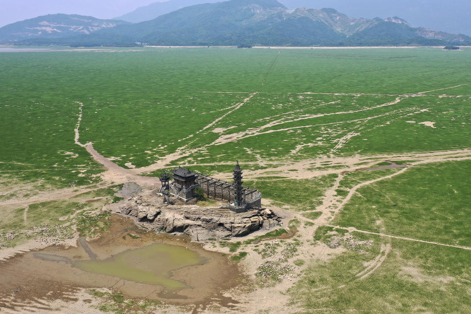 In this aerial photo released by China's Xinhua News Agency, Luoxingdun Island is seen in the dried lake bed of Poyang Lake, China's largest freshwater lake, in eastern China's Jiangxi Province on Aug. 17, 2022. With China's biggest freshwater lake reduced to just 25% of its usual size by drought, work crews are digging trenches to keep water flowing to irrigate crops. (Wan Xiang/Xinhua via AP)