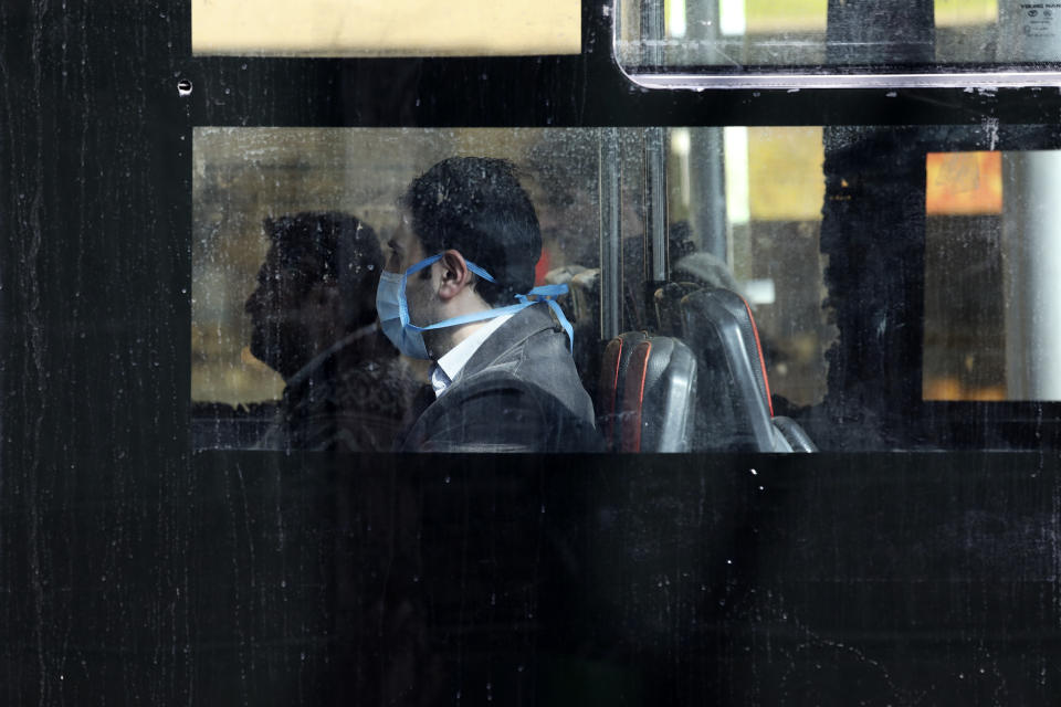 A man wearing a face mask travels on a public bus in northern Tehran, Iran, Sunday, March 1, 2020. While the new coronavirus has extended its reach across the world, geographic clusters of infections were emerging, with Iran, Italy and South Korea seeing rising cases. (AP Photo/Vahid Salemi)