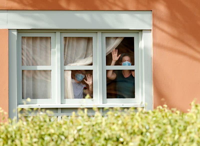 Guests, wearing protective face mask, look through a window at H10 Costa Adeje Palace, which is on lockdown after cases of coronavirus have been detected there in Adeje