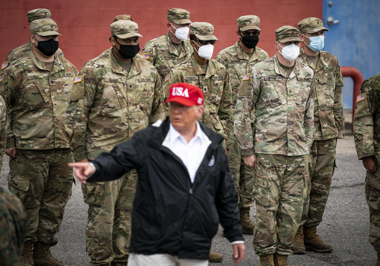 El presidente Donald Trump, que en ocasiones ha ridiculizado el uso de cubrebocas, con miembros de la Guardia Nacional de Luisiana, todos con tapabocas, en Lake Charles, Luisiana, el 29 de agosto de 2020. (Al Drago/The New York Times).