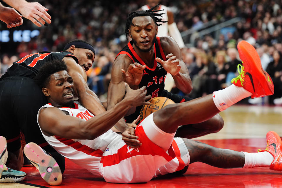 Houston Rockets forward Jae'Sean Tate, front, battles for the ball with Toronto Raptors forward Bruce Brown, left, and guard Immanuel Quickley, right, during the first half of an NBA basketball game Friday, Feb. 9, 2024, in Toronto. (Frank Gunn/The Canadian Press via AP)