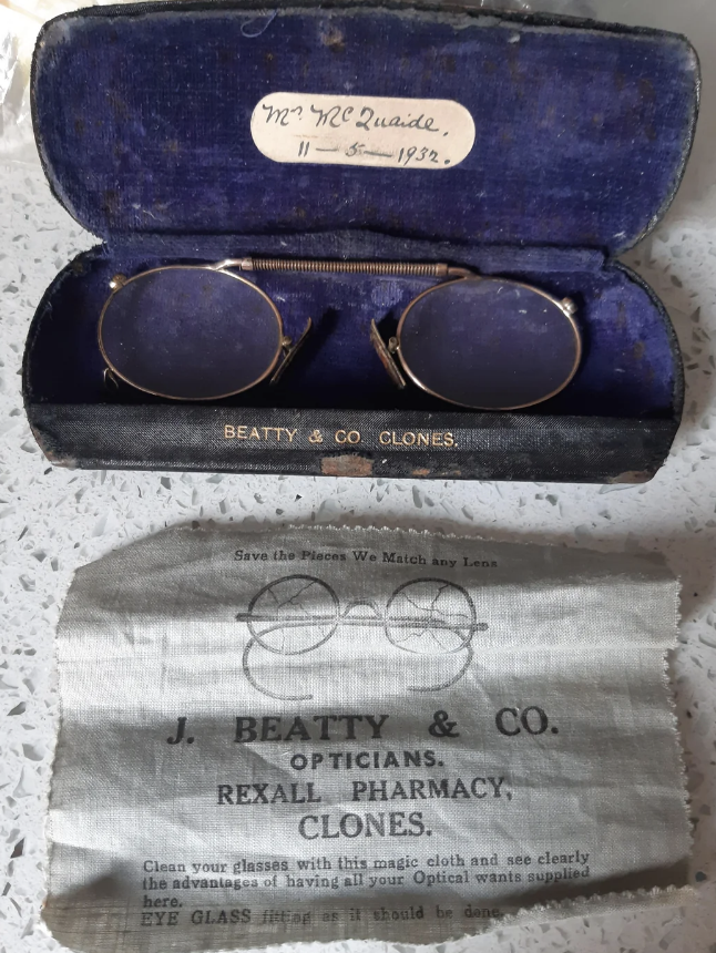 Vintage glasses in case with label "Mr WC Quaile, 5.11.1932" and a cloth from J. Beatty & Co. Opticians, Rexall Pharmacy, Clones