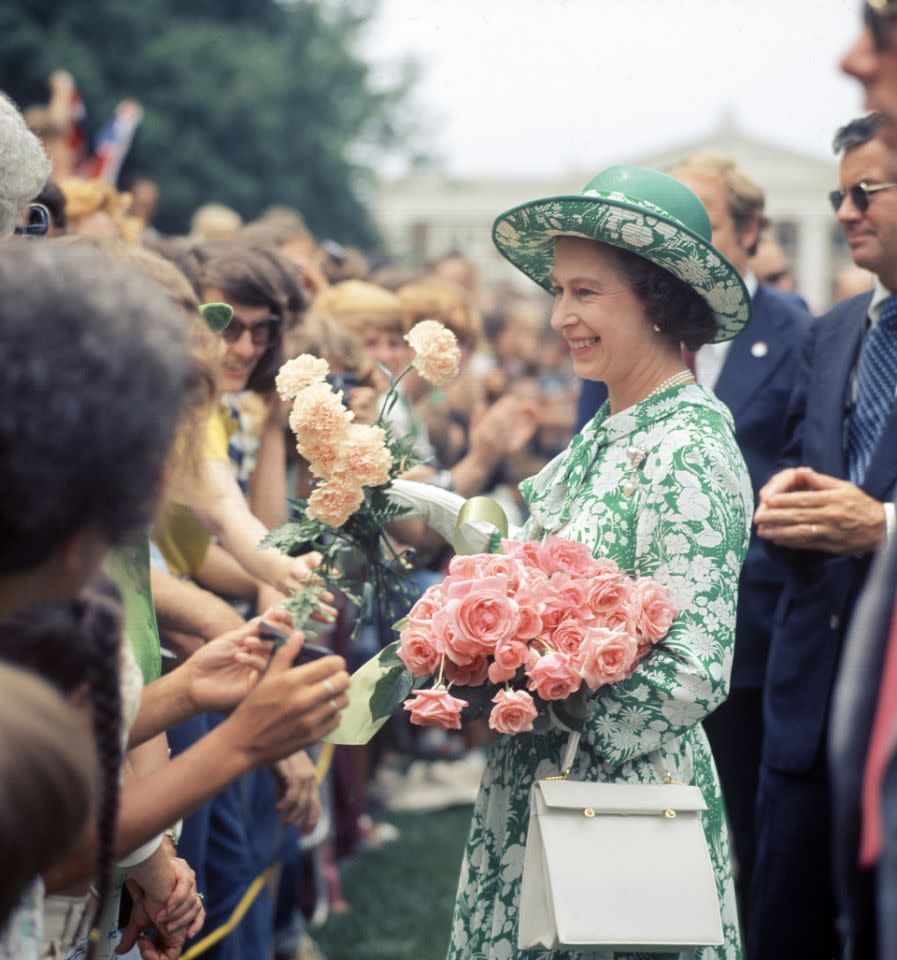 <p>Accepting flowers from students at the University of Virginia during a visit to the US, the Queen can be seen wearing a very summery green and white floral frock with matching hat. As usual, her pearls, white gloves and a brooch are in place. <i>[Photo: Rex]</i></p>