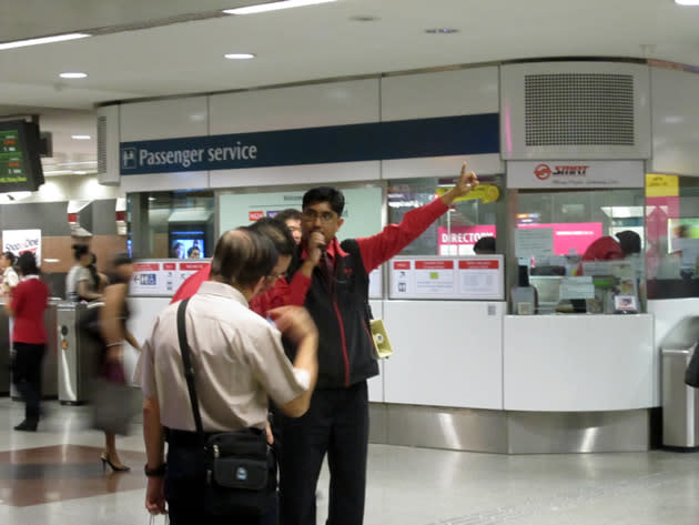 SMRT train staff were on hand to assist commuters affected by the train disruption, with some using microphones and loudspeakers to make announcements directing commuters to the right exits toward the bus stop where bridging services were offered. (Yahoo! photo/Jeanette Tan)