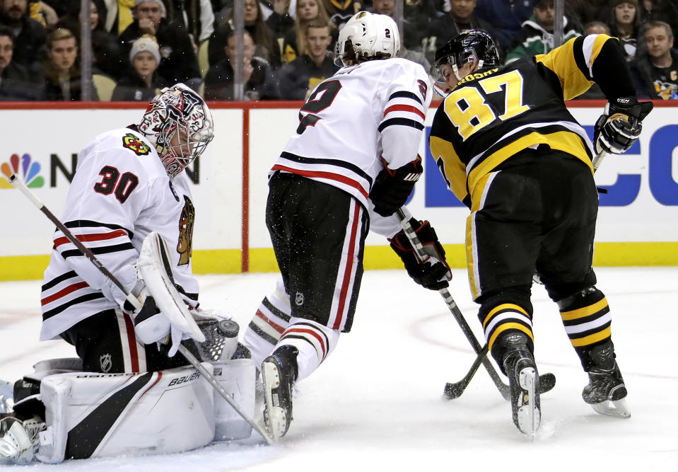 Chicago Blackhawks goaltender Cam Ward (30) stops a shot by Pittsburgh Penguins' Sidney Crosby (87) with Duncan Keith (2) defending during the second period of an NHL hockey game in Pittsburgh, Sunday, Jan. 6, 2019. (AP Photo/Gene J. Puskar)