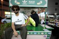 People pose for photos with Ravi X Adidas truck in front of the Ravi restaurant in Satwa district of Dubai, United Arab Emirates, Wednesday, June 22, 2022. Adidas has teamed up with Dubai nostalgic family-owned Pakistani restaurant to release the Superstar Ravi sneaker. (AP Photo/Kamran Jebreili)