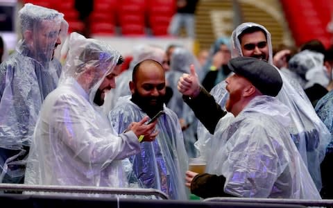 Fans enjoy the pre fight atmosphere in the stands while wearing rain coats at Wembley Stadium - Credit: Richard Heathcote/Getty Images