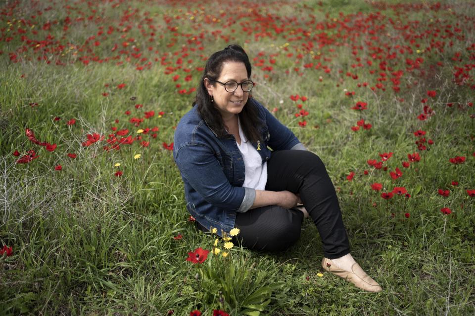 Vered Libstein posa para una fotografía sentada en un campo cubierto de flores anémonas silvestres cerca de Kibbutz Or HaNer, en el sur de Israel, el lunes 12 de febrero de 2024. (AP Foto/Maya Alleruzzo)