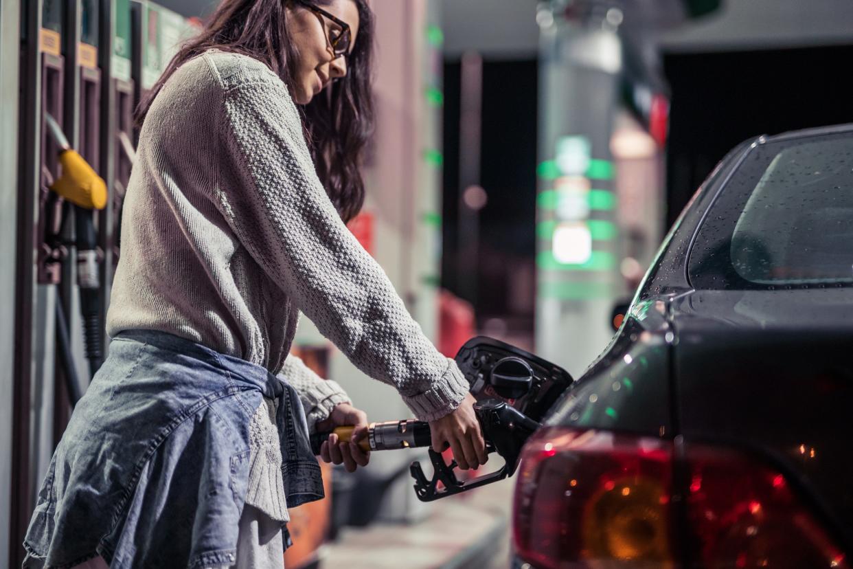 person adding gas to car at station