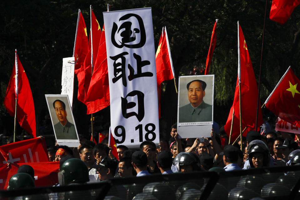 Anti-Japan protesters hold portraits of the late Communist leader Mao Zedong, Chinese national flags, and a poster that reads: "Sept. 18, National Humiliation Day," while marching on a street outside the Japanese Embassy in Beijing Tuesday, Sept. 18, 2012. The 81st anniversary of a Japanese invasion brought a fresh wave of anti-Japan demonstrations in China on Tuesday, with thousands of protesters venting anger over the colonial past and a current dispute involving contested islands in the East China Sea. (AP Photo/Alexander F. Yuan)