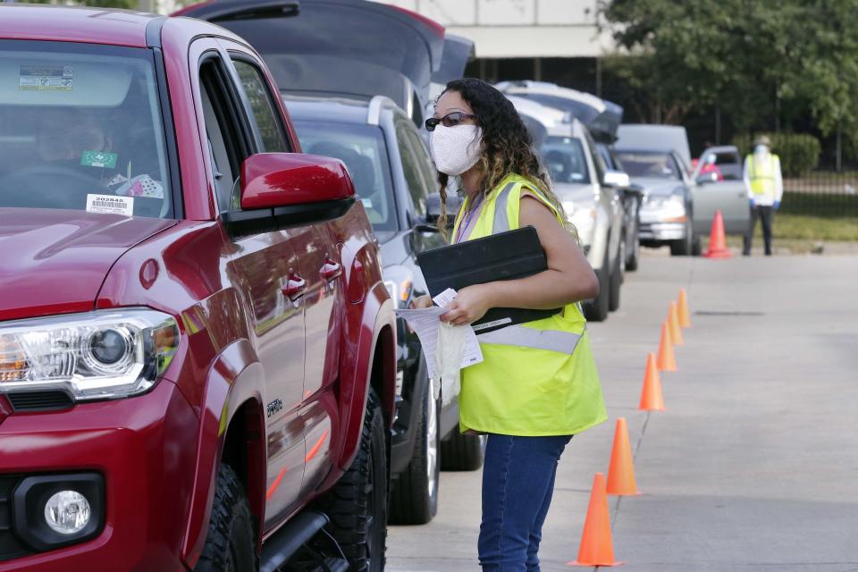 Volunteer Malia Alcaraz makes the last check on clients in the drive thru line before they receive food at the West Houston Assistance Ministries in Houston. 