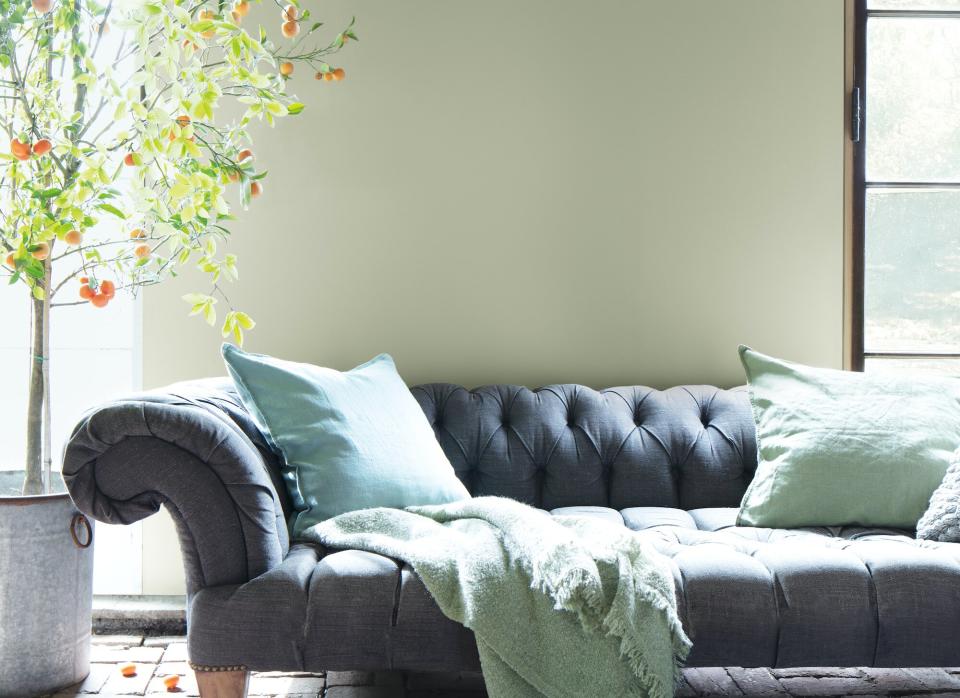 Sage green October Mist paint in living room with charcoal sofa: Benjamin Moore Color of the Year 2022, October Mist