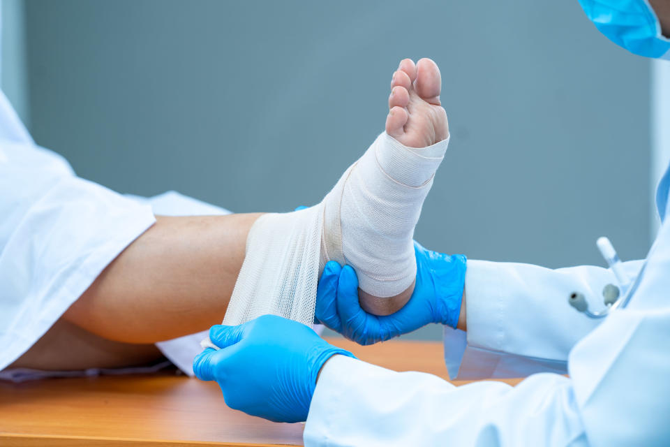 Patient getting injured ankle wrapped in tape