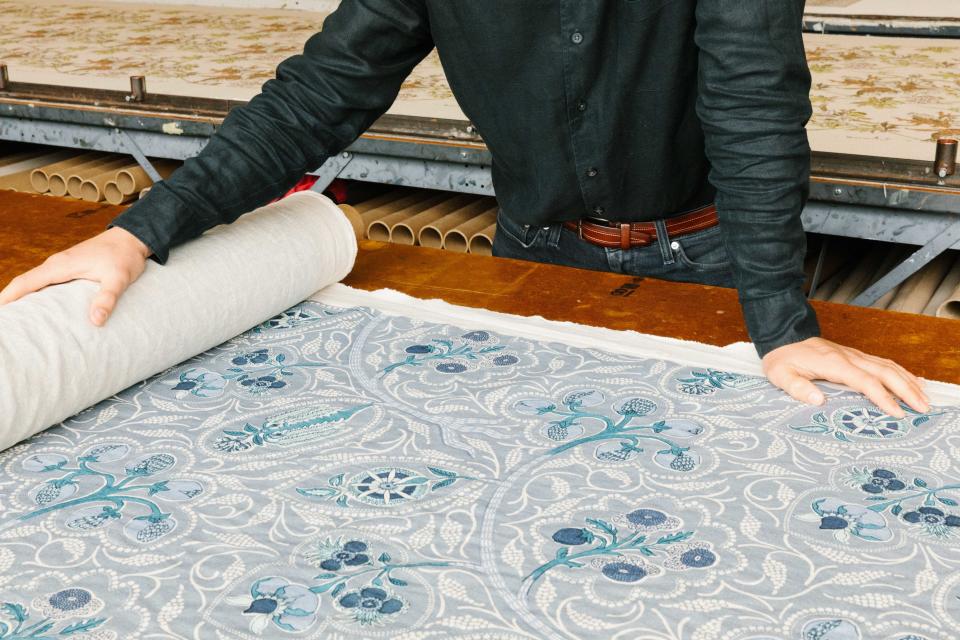 Gene unfurls a roll of freshly-printed fabric in the factory.