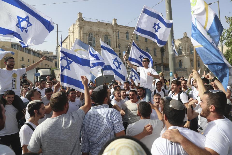 FILE - In this May 10, 2021, file photo, Israelis wave national flags during a Jerusalem Day march, in Jerusalem. At the last minute, the Israeli government ordered marchers to change their route, but by then it was too late. Hamas, saying it was protecting Jerusalem, launched a barrage of long-range rockets at the city, crossing an Israeli “red line” and sparking the war. (AP Photo/Ariel Schalit, File)