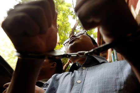 Detained Reuters journalist Wa Lone gives a thumbs up as he is escorted by police after a court hearing in Yangon, Myanmar April 4, 2018. REUTERS/Ann Wang/Files