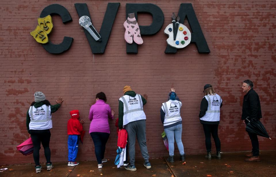 A group of visitors from the group "Pray for the Lou" place hands on the building during prayers at the site of a school shooting at Central Visual & Performing Arts High School in St. Louis, Tuesday, Oct. 25, 2022 in St. Louis. (Robert Cohen/St. Louis Post-Dispatch via AP)
