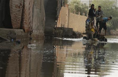 Palestinians ride a horse cart on a street flooded with sewage water from a sewage treatment facility in Gaza City November 14, 2013. REUTERS/Mohammed Salem